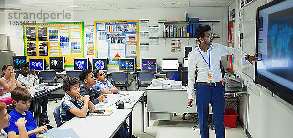 Männlicher Lehrer  der den Unterricht am Touchscreen im Klassenzimmer leitet