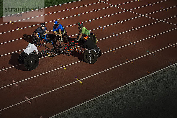 Querschnittsgelähmte Athleten kauern auf einer Sportbahn und trainieren für ein Rollstuhlrennen