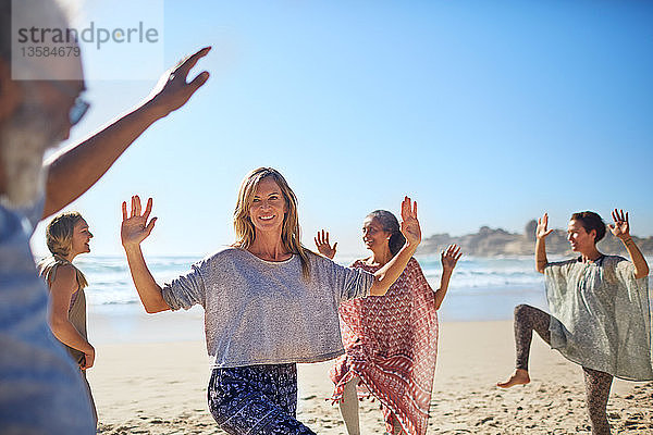 Tanzende Gruppe am sonnigen Strand während eines Yoga-Retreats