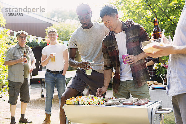 Männliche Freunde beim Grillen im sonnigen Sommergarten