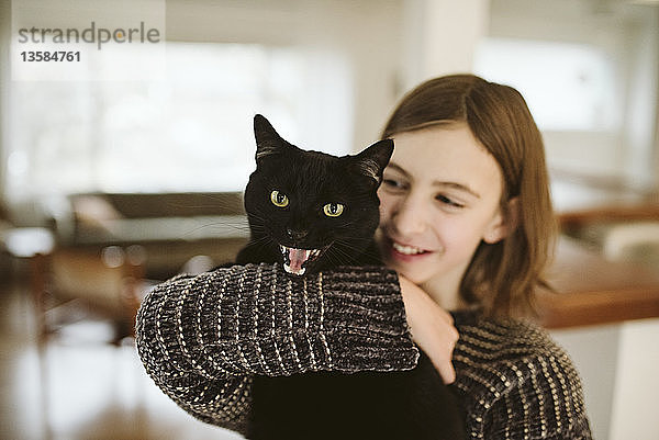 Porträt Mädchen hält fauchende schwarze Katze
