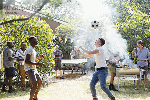 Männliche Freunde spielen Fußball und Tischtennis  genießen das Grillen im Hinterhof