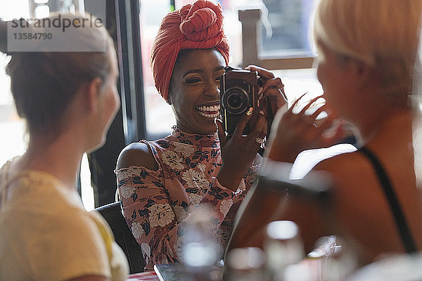 Junge Frau fotografiert Freund mit Digitalkamera in Café