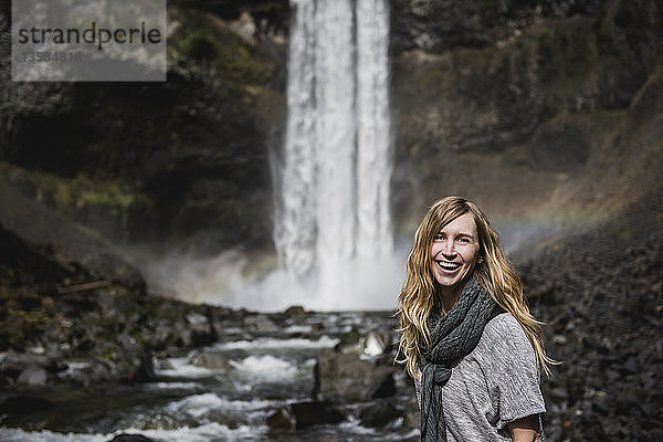 Porträt einer lächelnden  selbstbewussten Frau beim Wandern entlang eines Wasserfalls  Whistler  British Columbia  Kanada