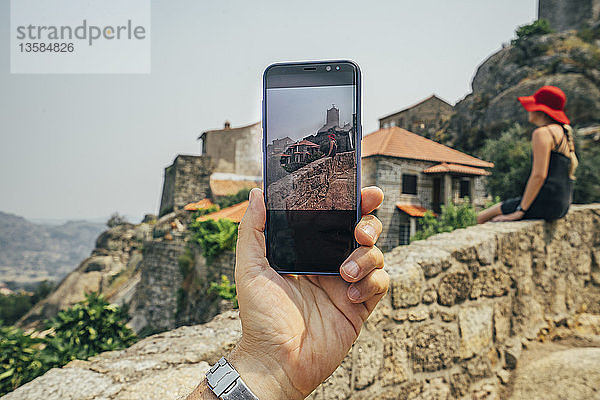 Persönliche Perspektive Mann mit Fotohandy fotografiert Frau auf Steinmauer  Monsanto  Portugal