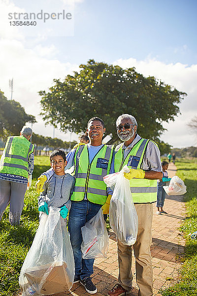 Porträt glücklicher Mehrgenerationen-Männer  die freiwillig Müll in einem sonnigen Park aufräumen