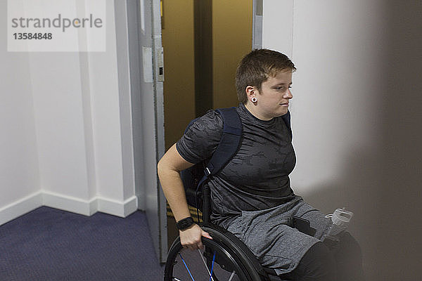 Junge Frau im Rollstuhl beim Verlassen des Aufzugs