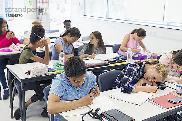 Schüler der Junior High School lernen an Tischen im Klassenzimmer