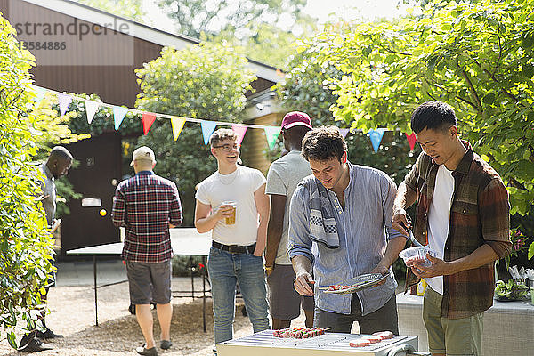 Männliche Freunde genießen das Grillen im sonnigen Hinterhof