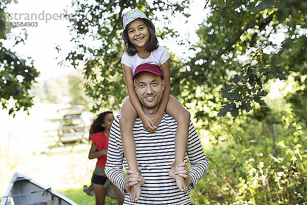 Porträt Vater trägt Tochter auf den Schultern im Wald