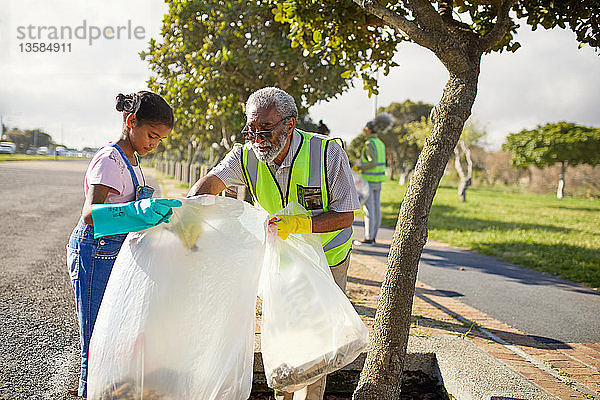 Großvater und Enkelin säubern freiwillig den Müll im sonnigen Park