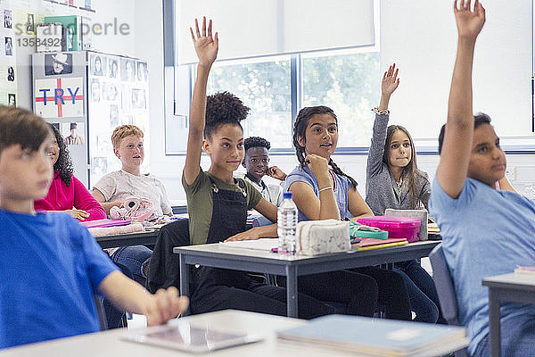 Gymnasiasten mit erhobenen Händen im Klassenzimmer