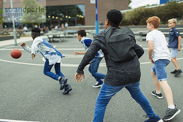 Schüler der Junior High spielen Basketball auf dem Schulhof