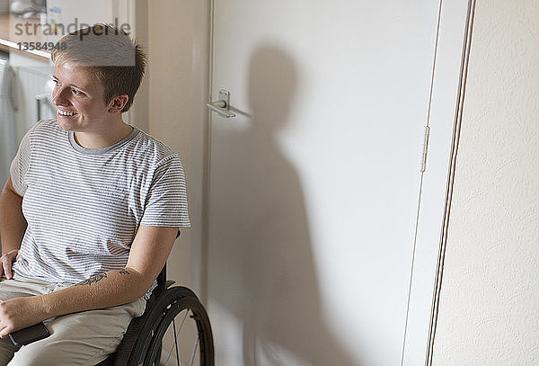 Lächelnde junge Frau im Rollstuhl zu Hause