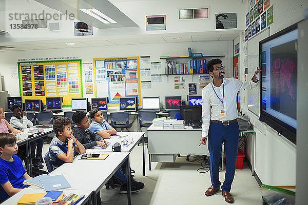 Männlicher Lehrer  der den Unterricht am Touchscreen im Klassenzimmer leitet