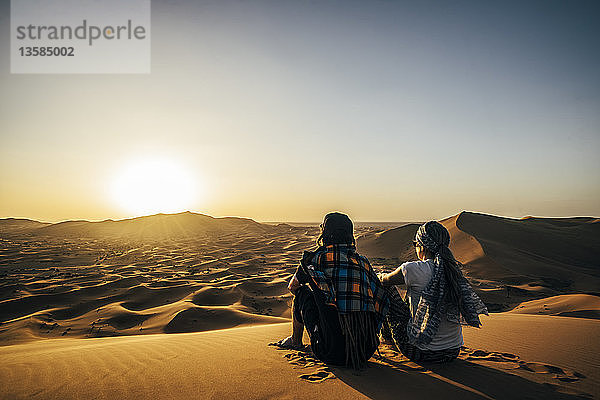 Ein Paar genießt die sonnige Aussicht auf eine abgelegene Sandwüste  Sahara  Marokko