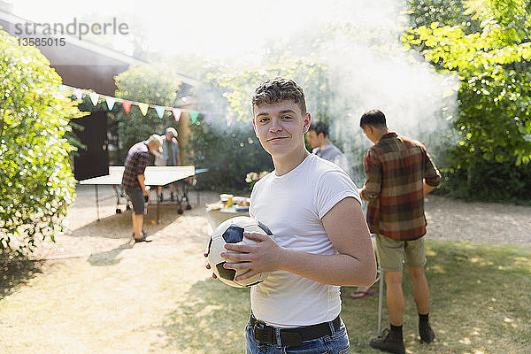 Porträt selbstbewusster Jugendlicher mit Fußball  der im Hinterhof grillt