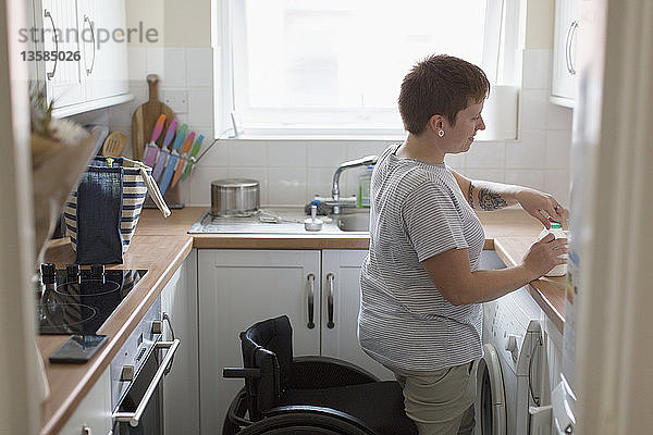 Junge Frau mit Rollstuhl in der Wohnküche