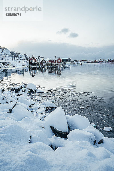 Malerische  verschneite Aussicht auf ein Fischerdorf am Wasser  Reine  Lofoten Inseln  Norwegen