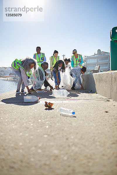 Freiwillige Helfer sammeln Plastikmüll an der sonnigen Strandpromenade auf