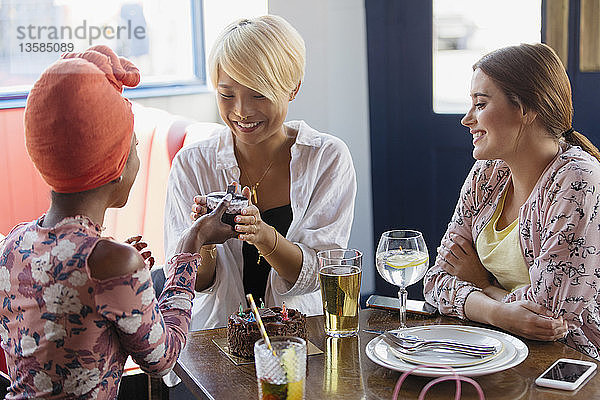 Junge Frau gibt Geburtstagsgeschenk an Freund in Restaurant