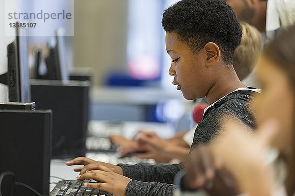 Fokussierter Schüler der Junior High School bei der Benutzung eines Computers im Computerraum