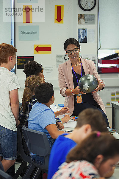 Geografielehrerin mit Globus beim Unterricht im Klassenzimmer