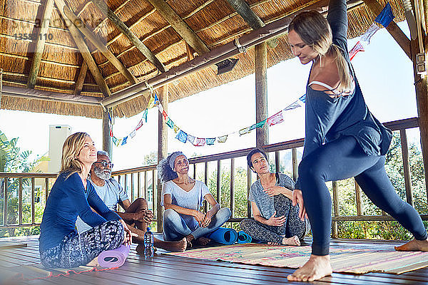 Weibliche Lehrerin demonstriert die Seitenwinkelhaltung in einer Hütte während eines Yoga-Retreats