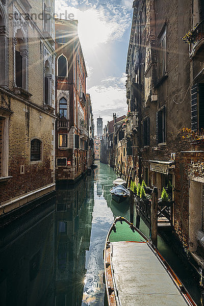 Die Sonne scheint über ruhige Gebäude und einen Kanal mit Gondeln  Venedig  Italien