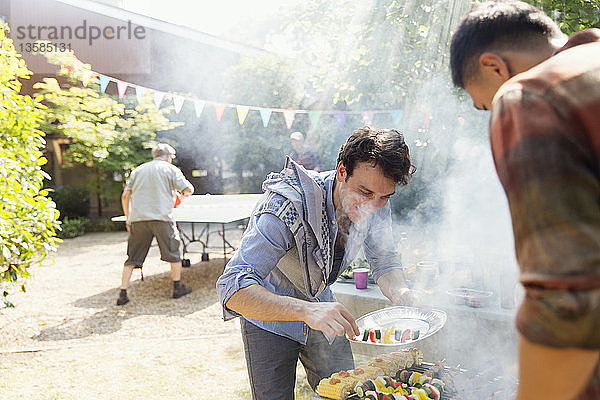 Männliche Freunde beim Grillen im sonnigen Hinterhof