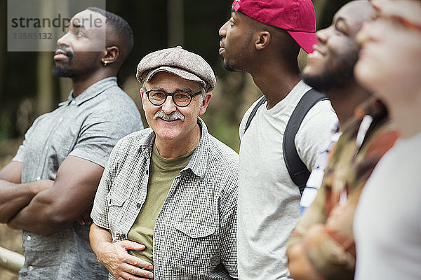Porträt lächelnder älterer Mann mit Männergruppe