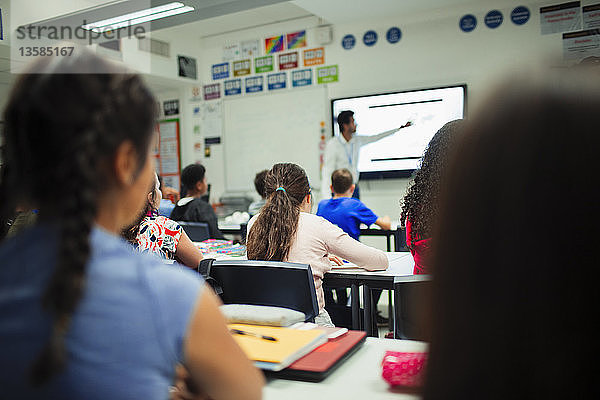 Schüler der Junior High School beobachten den Unterricht des Lehrers auf der Projektionsfläche im Klassenzimmer