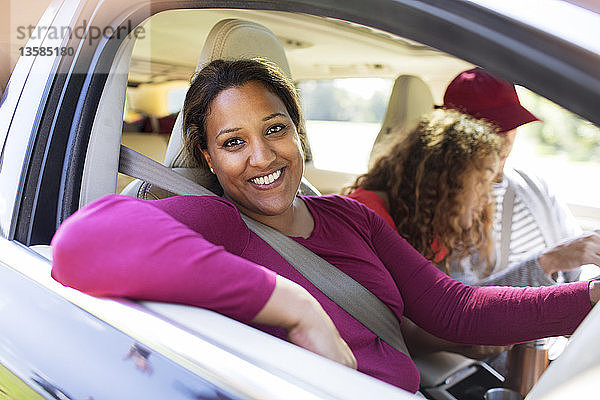 Porträt glückliche Frau im Auto mit Familie auf Autoreise