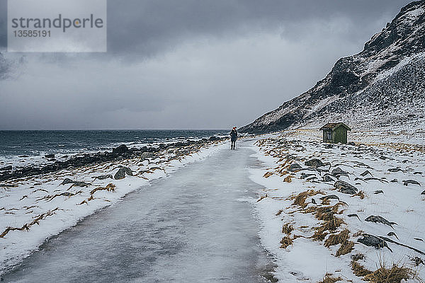 Frau geht am vereisten Strand entlang  Lofoten-Inseln  Norwegen