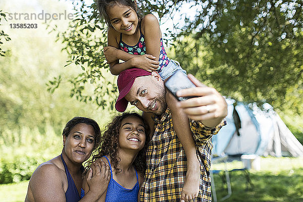 Glückliche  liebevolle Familie macht Selfie mit Fotohandy auf dem Campingplatz