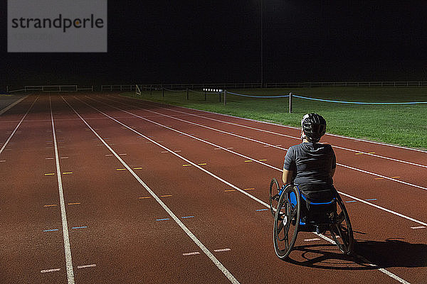 Entschlossene querschnittsgelähmte Sportlerin  die nachts auf einer Sportbahn für ein Rollstuhlrennen trainiert