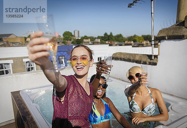 Porträt zuversichtlich  sorglos junge Frauen Freunde trinken Champagner in sonnigen Dachterrasse Whirlpool