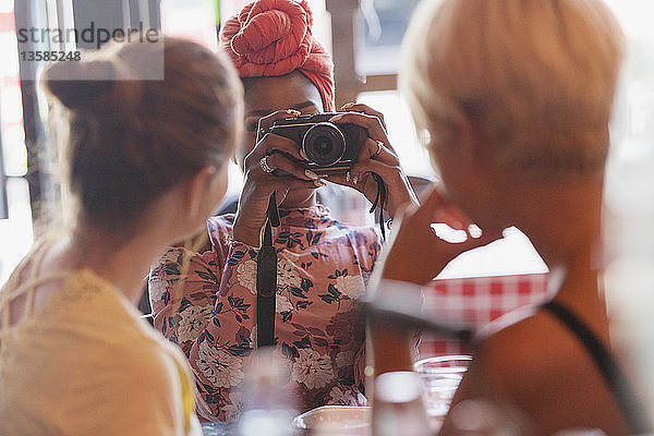 Junge Frau fotografiert Freunde mit Kamera im Restaurant