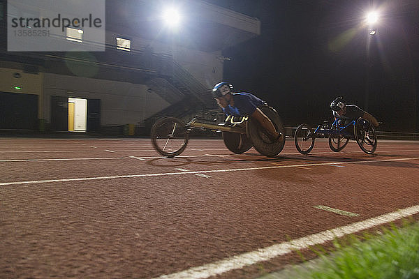 Querschnittsgelähmte Athleten rasen bei einem nächtlichen Rollstuhlrennen über eine Sportstrecke