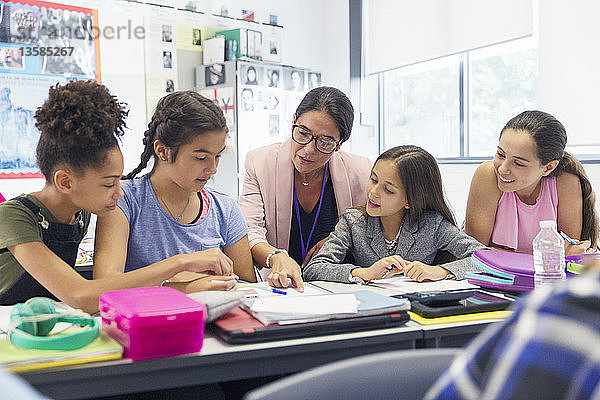 Weibliche Lehrerin und Schülerin der Junior High School lernen am Schreibtisch im Klassenzimmer