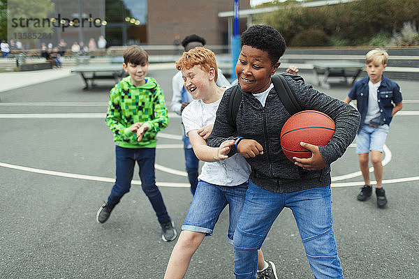 Zwei Jungen spielen Basketball auf dem Schulhof