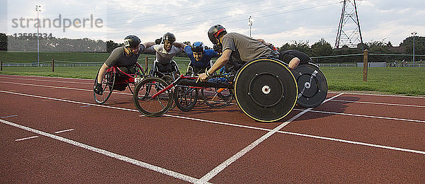 Entschlossene querschnittsgelähmte Athleten trainieren gemeinsam für ein Rollstuhlrennen auf dem Sportplatz