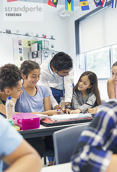 Lehrerin hilft Schülern der Junior High School am Schreibtisch im Klassenzimmer