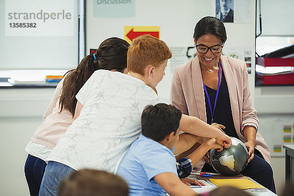 Schüler der Junior High School zeigen auf den Globus in den Händen eines Geografielehrers