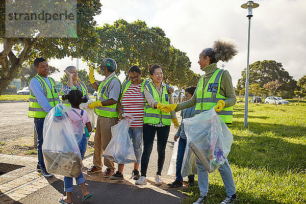 Fröhliche Freiwillige  die feiern und Müll aus dem sonnigen Park entfernen