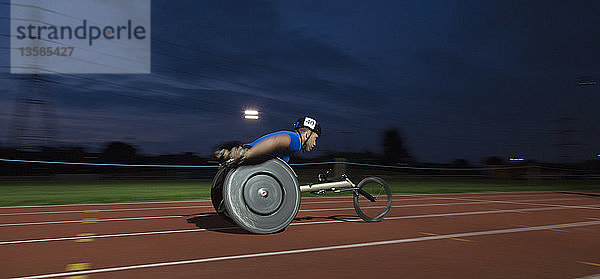 Junger querschnittsgelähmter Sportler  der bei einem nächtlichen Rollstuhlrennen über eine Sportstrecke rast