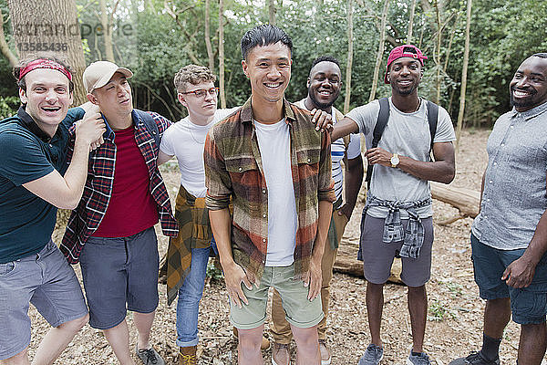 Porträt einer fröhlichen  unbekümmerten Männergruppe beim Wandern im Wald