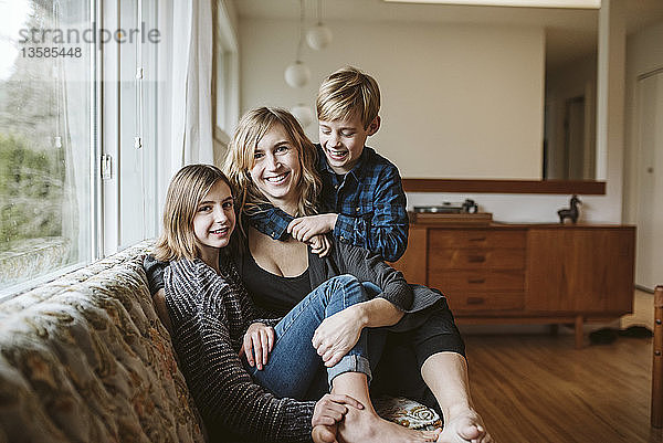 Portrait glückliche Mutter und Kinder kuschelnd auf dem Wohnzimmersofa