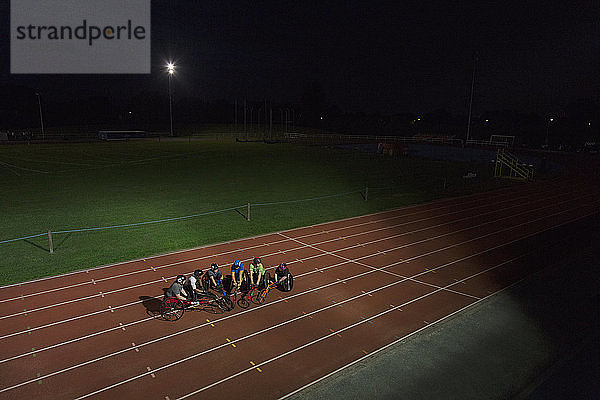 Querschnittsgelähmte Athleten trainieren nachts auf der Sportanlage für ein Rollstuhlrennen