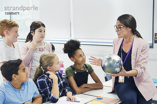 Aufmerksame Schüler der Mittelstufe beobachten den Geografielehrer mit dem Globus